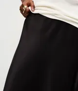 Pollera midi de satén color negro, con corte evasé y cintura elástica. Presenta una caída fluida y suave con acabado brillante.