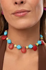 Gargantilla corta multicolor compuesta por cuentas de acrílico turquesas, piedras naturales amarillas y colgantes en forma de gota de cristal checo rojo estriado.
