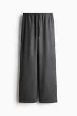Pantalón de corte holgado y piernas rectas, confeccionado en tejido con textura de espiguilla. Presenta cintura elástica con cordón de ajuste, bolsillos laterales y bolsillos traseros decorativos.