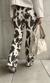 Pantalón de jean de corte recto con estampado de manchas de vaca en tonos marrón y blanco.