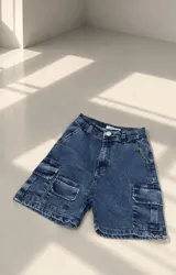Short de denim azul con diseño cargo, múltiples bolsillos laterales con solapa, tiro alto y trabillas para cinto.