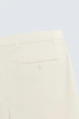 Bermuda de hombre color beige claro, corte regular fit, con pliegues frontales, bolsillos delanteros y bolsillos traseros de doble vivo con botón.