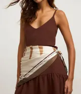 Pañuelo satinado de poliéster con estampado geométrico en tonos beige, blanco y marrón, con detalles de puntos.