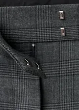 Pantalón de traje gris con sutil diseño de cuadros, tiro medio y pernera recta. Cuenta con trabillas para cinturón, pinzas delanteras, bolsillos laterales y cierre frontal con cremallera, botón y ganchos ocultos.