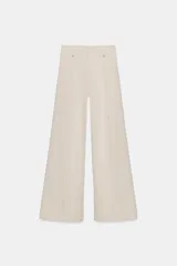 Jeans de tiro alto confeccionados en mezcla de algodón, con diseño de pierna ancha y costura marcada en el delantero. Presenta cintura con trabillas, cierre frontal con cremallera, botón y gancho metálico, y bolsillos de plastrón en la espalda.