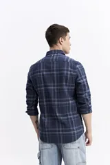 Camisa de manga larga confeccionada en viyela de algodón con diseño de cuadros en tonos azul y verde. Presenta cierre frontal con botones, cuello clásico y bolsillo en el pecho.