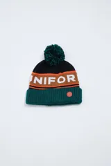 Gorro de lana tejido con pompón verde, con banda horizontal marrón con la palabra "UNIFORM" en blanco y base verde.