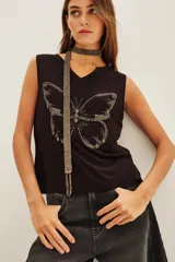 Musculosa negra con escote en V y aplique de mariposa hecho con tachas plateadas. Se complementa con un accesorio tipo choker/collar largo de cuentas plateadas.