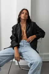 Blazer de eco cuero negro con hombreras, solapas clásicas y cierre frontal con botones.