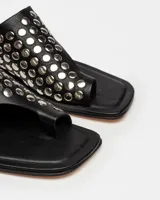 Sandalias planas blancas de cuero, con tira ancha sobre el empeine adornada con tachas plateadas.