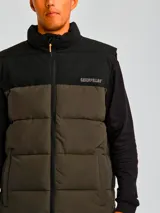 Chaleco acolchado bicolor con diseño de bloques en negro y verde oliva. Presenta cierre frontal completo, cuello alto, bolsillos laterales con cierre y logo de la marca estampado en el pecho.
