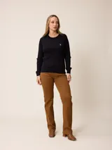 Sweater de punto con diseño de trenzas verticales, color negro, con cuello redondo, mangas largas y puños con detalle en contraste blanco. Presenta un pequeño logo bordado en el pecho.