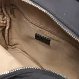 Mochila urbana de tamaño pequeño, confeccionada en material textil color negro. Presenta dos bolsillos frontales con cierre metálico, tiradores con detalle de argollas y cordón trenzado decorativo. Incluye logo circular de la marca en la parte inferior central.