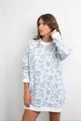 Buzo de punto con diseño estampado floral en tonos blanco y azul, de corte holgado y largo tipo vestido, con cuello redondo y mangas largas.