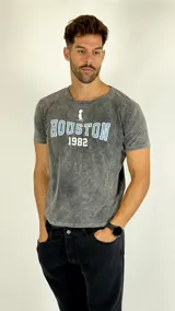 Remera de algodón con efecto lavado ácido en color gris, de corte clásico y manga corta. Presenta un estampado frontal con la palabra 'HOUSTON' en letras celestes con borde blanco, el número '1982' en blanco y un pequeño ícono superior.