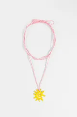 Collar largo de cordón rosado con dije colgante en forma de sol con diseño en espiral de color amarillo.