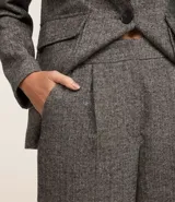 Pantalón de vestir gris con textura tweed, de corte recto, cintura alta con pliegues delanteros y bolsillos laterales.