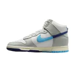 Championes Nike Dunk High Retro SE de corte alto, con diseño en paneles de cuero blanco y gris. Presenta un swoosh lateral dividido en dos tonos de azul, suela intermedia con acabado envejecido y suela exterior bicolor en azul claro y oscuro.