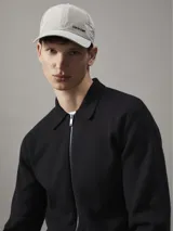 Gorra de béisbol color beige con logo metálico de Calvin Klein en el lateral.