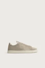 Zapatilla de piel con acabado en serraje de color gris, diseño de cordones ocultos y suela de goma en contraste de color blanco.