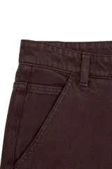 Pantalón estilo skater de corte holgado, color marrón oscuro, con cierre de botón y cremallera, bolsillos laterales y traseros.