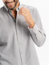 Camisa de corte regular confeccionada en tejido oxford, color azul claro. Presenta cuello con botones, cierre frontal abotonado, mangas largas con puños y un bolsillo frontal en el pecho.