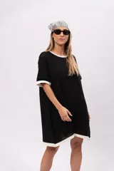 Vestido corto negro de tejido de punto calado, con cuello redondo y mangas cortas con ribete blanco.