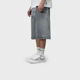 Bermuda baggy de denim gris, corte holgado y largo por debajo de las rodillas, con dobladillo desmechado.