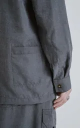 Camisa de manga larga color grafito, estilo técnico con múltiples bolsillos delanteros con tapa y botones en cartera y puños. Presenta un calce oversize y está confeccionada en textil ligero y suave al tacto.