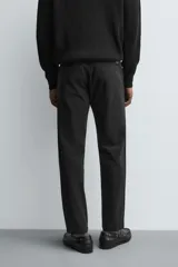 Pantalón chino de corte ajustado, color beige, con bolsillos laterales y bolsillos traseros de vivo. Cuenta con cierre frontal de cremallera y botón.