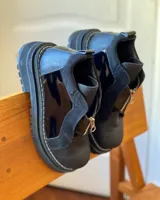 Botinetas de cuero combinadas en color negro y marrón, con diseño de paneles, cierre frontal y suela track dentada.