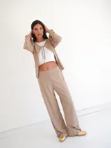 Pantalón de corte recto y pierna ancha, confeccionado en tejido ligero color beige, con cintura elástica.