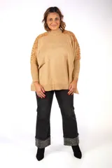 Sweater de punto color beige, con cuello alto y diseño holgado. Presenta detalles de encaje floral en los hombros y mangas, con puños acanalados.