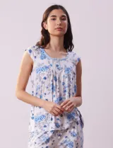 Conjunto de pijama marca René Rofé, compuesto por remera de mangas cortas con escote en V abotonado y pantalón capri con cintura elastizada. Diseño estampado con flores azules sobre fondo blanco.