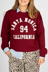 Sweater bordó de corte clásico con estampa frontal con la leyenda 'Santa Monica 94 California' en color blanco.