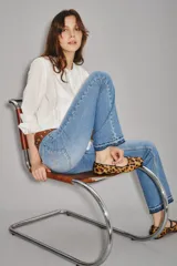 Jean de corte recto y tiro medio, confeccionado en denim de algodón en tono azul lavado. Presenta un diseño clásico con costuras decorativas en los bolsillos traseros y un detalle de bordado sutil en el ruedo.