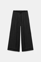 Pantalón de tiro medio, color negro, confeccionado en tejido satinado con diseño de pierna ancha y cintura elástica ajustable con cordón.