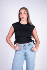 Remera entallada blanca de manga corta y cuello redondo, confeccionada en tejido rib con detalles de tiras ajustables fruncidas en los costados.