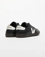 Championes urbanos Veja modelo Panenka O.T. Leather, color negro con detalles en blanco en el logo lateral y talón. Presentan una suela de goma color marrón oscuro y cierre con cordones.