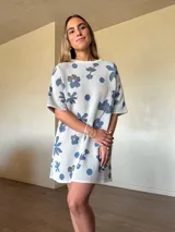 Vestido corto de tejido de algodón con detalles de lúrex, color blanco, con estampado floral y de lunares en tonos azules y dorados. Presenta cuello redondo y mangas cortas de corte holgado.