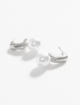 Aros plateados con forma de gancho y perlas artificiales blancas.