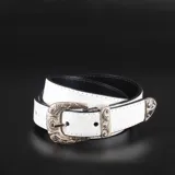 Cinturón blanco con textura croco, forrado en cuero negro y hebilla metálica plateada con diseño labrado.