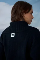 Cardigan negro de punto con cuello tipo polo y cierre frontal de botones. Presenta un diseño de textura acanalada y corte ajustado.