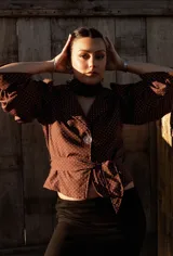 Camisa blanca con lunares celestes, de corte clásico, con cuello camisero y mangas largas abullonadas.