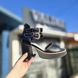 Sandalias de cuero color suela y beige, con plataforma de madera, taco ancho y doble tira con hebillas metálicas en el tobillo. Cuentan con cierre trasero.
