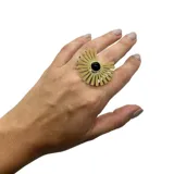 Anillo dorado con forma de sol y piedra negra central, de acero inoxidable y tamaño regulable.