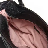 Cartera chica de símil cuero color negro, de diseño estructurado con doble asa de mano y correa de hombro ajustable y desmontable. Cuenta con detalles de cordones fruncidos en los laterales y el logo metálico de la marca en la parte frontal.