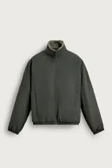Cazadora relaxed fit de tejido técnico color gris oscuro, con interior de borreguillo, cuello subido y cierre frontal de cremallera. Cuenta con bolsillos laterales con cremallera y acabados elásticos en puños y cintura.