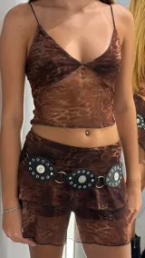 Short pollera tiro bajo con estampado animal print en tonos marrones y negros. La prenda es de tela transparente y ajustada al cuerpo.