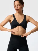 Top deportivo negro con detalle de nudo en el centro del busto y tirantes anchos. Confeccionado en poliéster con spandex.